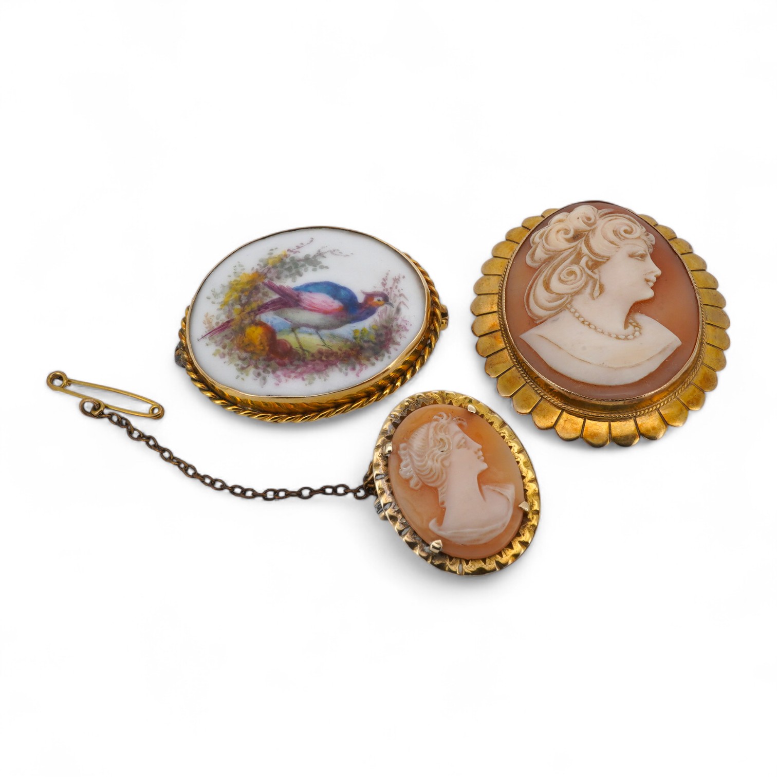 Three brooches, comprising: two shell cameo brooches, each mounted in 9ct gold, largest 4.5cm; and an enamel brooch depicting a pheasant, mounted in gold, length 3.7cm, stamped 9CT